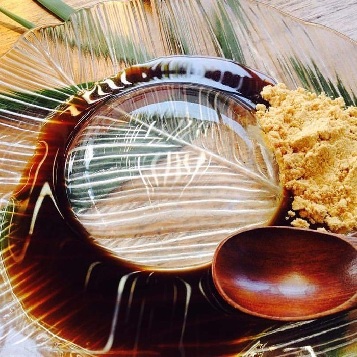 A clear water-drop wagashi served with kinako and dark syrup